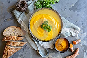 Delicious creamy carrot soup with turmeric powder and baguette