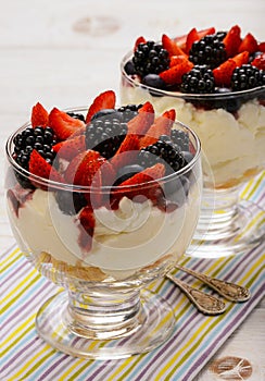 Delicious creamy dessert with biscuits, strawberries, blackberries and blueberries.