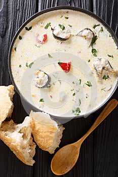 Delicious creamy fish soup with eel, cheese and vegetables close-up in a bowl. Vertical top view