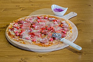 Delicious crepe pizza with sausage on wooden board with slicer