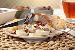 Delicious crepes with banana, nuts and chocolate paste on table, closeup