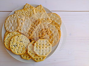 Delicious crisp salty crackers on plate on white background.