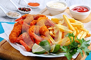 Delicious crispy crunchy parmesan bread crumbs coating Fried Shrimps with lime wedges, french fries and parsley