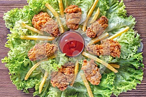 Delicious crispy fried chicken wings on green salad, closeup