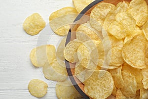 Delicious crispy potato chips in bowl on table, space for text