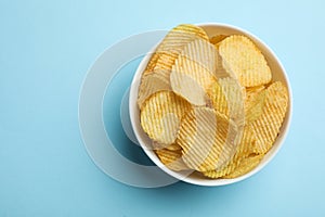 Delicious crispy potato chips in bowl, top view with space for text