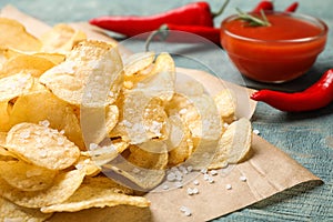 Delicious crispy potato chips with salt on table