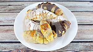 Delicious croissants with chocolate and powder sugar served on white plate for desert or breakfast