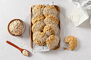 Delicious and crunchy oatmeal cookies, oatmeal flakes and a cup of milk on white background. Copy space. Recipe, bakery menu,
