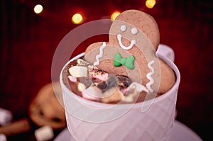 Delicious cup of hot chocolate with a gingerbread man cookie dipped in cinnamon sprinkled chocolates, ideal for a Christmas card