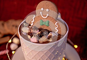 Delicious cup of hot chocolate with a gingerbread man cookie dipped in cinnamon sprinkled chocolates, ideal for a Christmas card