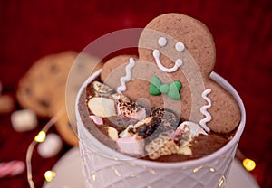 Delicious cup of hot chocolate with a gingerbread man cookie dipped in cinnamon sprinkled chocolates, ideal for a Christmas card