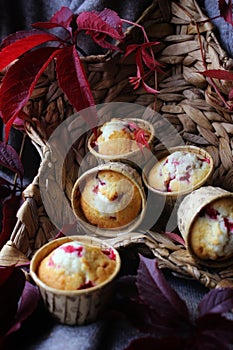 delicious cupcakes and burgundy leaves in a basket on a dark background. homemade baked goods, abstract background. dessert