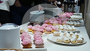 Delicious cupcakes on candy buffet, people takes food from smorgasbord