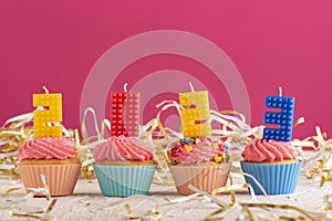 Delicious cupcakes decorated with candles in form of numbers 2023 on pink background. New Years Eve Celebration