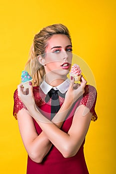 Delicious cupcakes. Fashion girl eating food, eating colorful cupcakes. Sensual woman in elegant dress. Fashion makeup, hairstyle