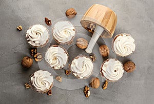 Delicious cupcakes with walnuts on grey table