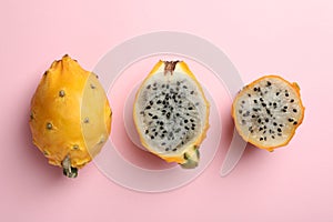 Delicious cut and whole dragon fruits pitahaya on pink background, flat lay