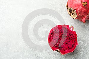 Delicious cut and whole red pitahaya fruits on light grey table, flat lay. Space for text