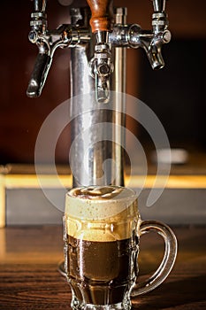 Delicious dark craft beer filled into a pint glass on wooden table