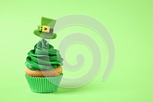 Delicious decorated cupcake on green background, space for text. St. Patrick`s Day celebration