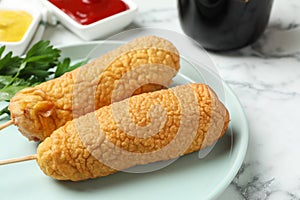 Delicious deep fried corn dogs on white marble table, closeup