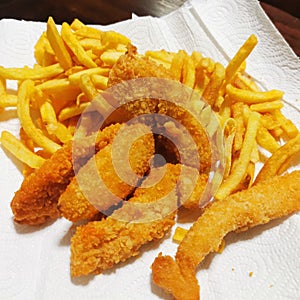 Delicious deep-fried fish sticks, chips, and chickens on a paper tissue