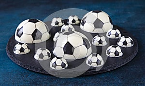 A delicious dessert of chocolate football balls of different shapes on a black serving plate - a concept of sports photography for