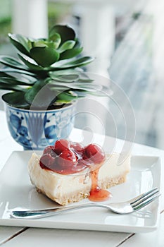 Delicious with dessert a piece of cherry cheesecake and black coffee on white tone wooden table