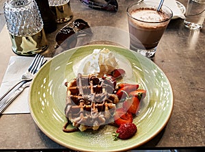 Delicious dessert with waffles, strawberries, cream and hot chocolate with sunglasses summer