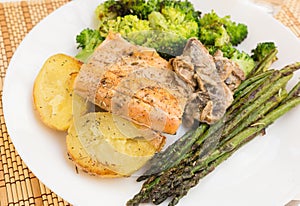 Delicious dish of fried river trout fillet with garnish of broccoli, asparagus sprouts, baked potatoes and mushroom