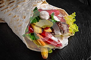 A delicious doner donair kebab wrap with meat, lettuce, tomato, red onion photo