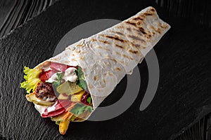 A delicious doner donair kebab wrap with meat, lettuce, tomato, red onion photo