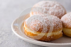 delicious donuts berliners with filling sprinkled with powdered sugar on a white plate photo