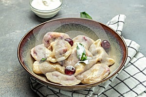 Delicious dumplings with cherries and cream sauce, Food recipe background. Close up, top view