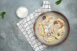 Delicious dumplings with cherries and cream sauce, Food recipe background. Close up, top view