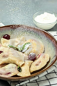 Delicious dumplings with cherries and cream sauce, Food recipe background. Close up, top view