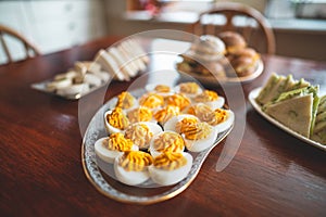 Delicious easter brunch with homemade sandwiches, buns and filled eggs on a wooden kitchen table