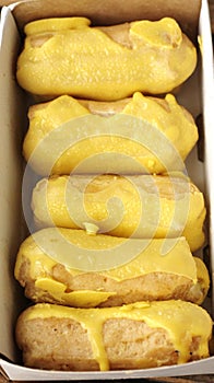 Delicious eclairs with yellow glaze in a box