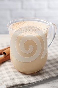 Delicious eggnog with cinnamon on wooden table, closeup