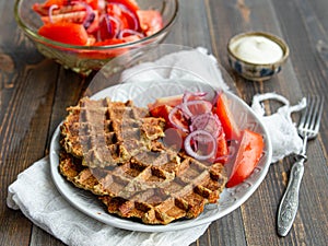 Delicious eggplant wafflese inwhite ceramic plate with tomato and onion salad and sauce ion wood background. Healthy
