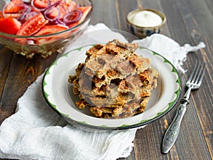 Delicious eggplant wafflese in retro metal plate with tomato and onion salad and sauce ion wood background. Healthy