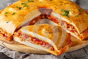 Delicious Empanada Gallega round Spanish pie filled with meat and vegetables close-up on a board. Horizontal