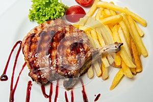 Delicious entrecote grilled steak on white plate with french fries and decorated with sauce.