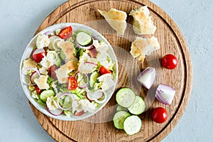 Delicious fattoush salad with bread pita, fresh vegetables and basil on plate on the wooden stand. Traditional middle eastern