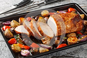 Delicious festive baked pork loin with vegetables and mushrooms close-up on a baking sheet. Horizontal