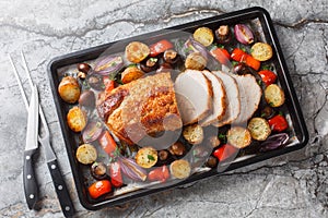 Delicious festive baked pork loin with vegetables and mushrooms close-up on a baking sheet. Horizontal top view