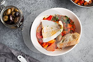 Delicious fish stew in paprika, tomatoes and white wine. Cod fillet white sea fish with organic vegetables, olives