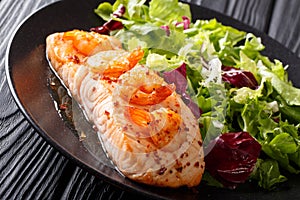 Delicious food: baked salmon with prawns in honey sauce and fresh salad on a plate close-up. horizontal