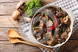 Delicious food: beef stew with wild mushrooms in spicy sauce close-up in a bowl. Horizontal top view